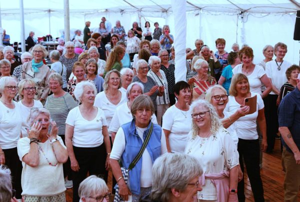 A big group of smiling older people gather in a giant marquee to celebrate the BALL Groups anniversary.