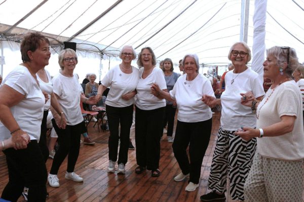 A line-up of seven old women, all with white T-shirts, look ready to dance.
