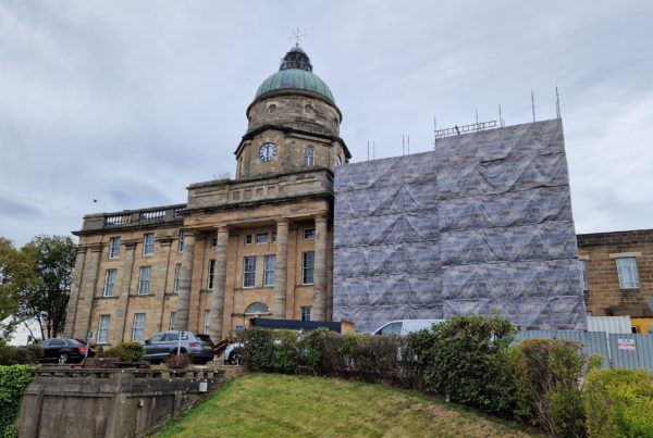 Front view of the Dr Gray's Hospital building In Elgin, showing the iconic sandstone walls, clocktower. Part of the right hand side of the building is obscured by scaffolding.