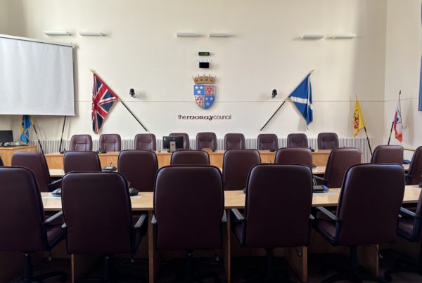 An interior view of the Moray Council chambers, taken rom the back to show the rows of seats with the raised top table.